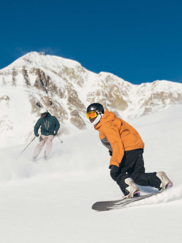 Skier and snowboarder in front of Lone Peak