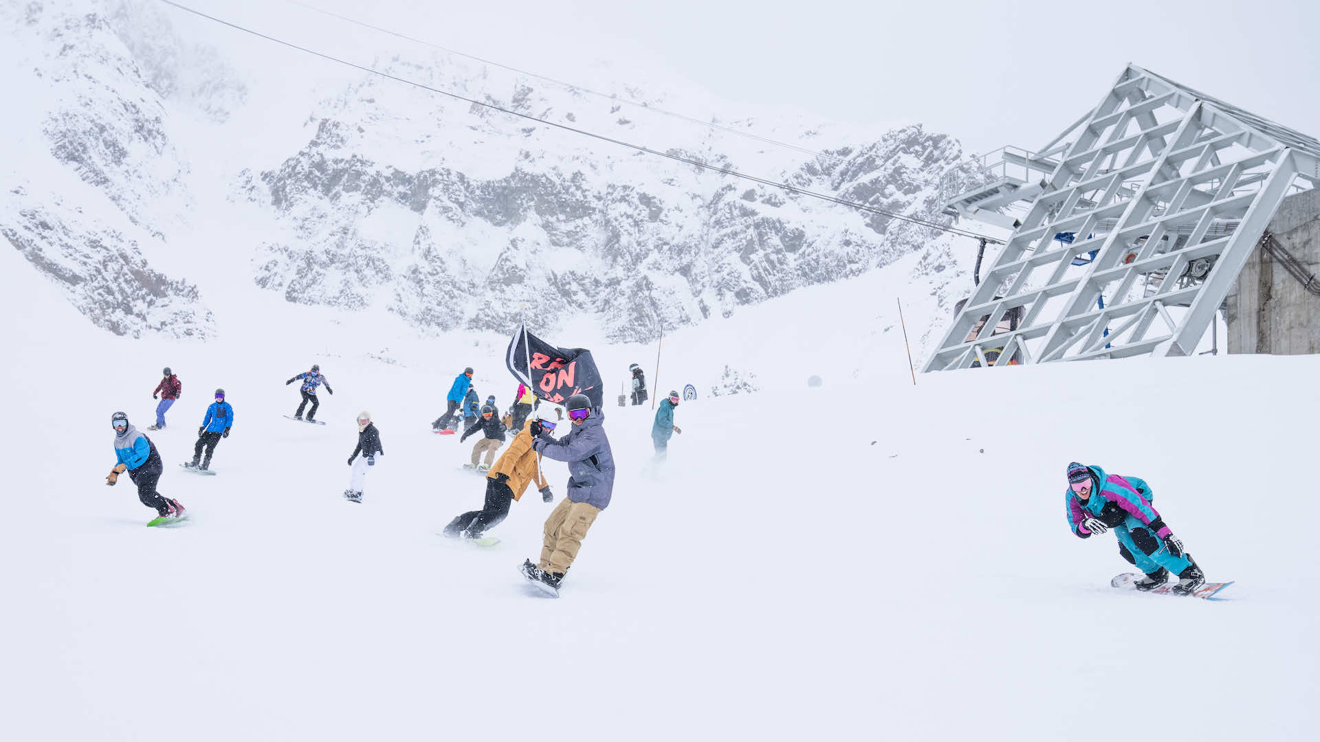 A group of snowboarders with one carrying a flag
