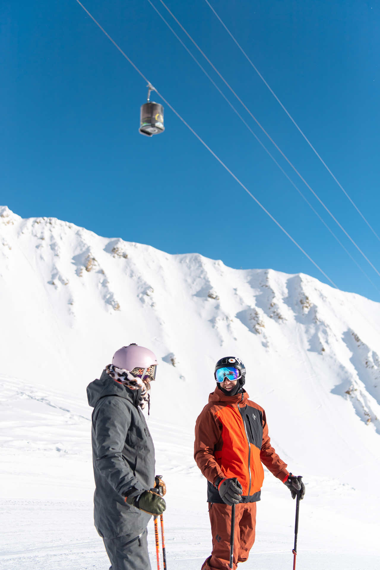 Couple in ski gear standing underneath the Lone Peak Tram